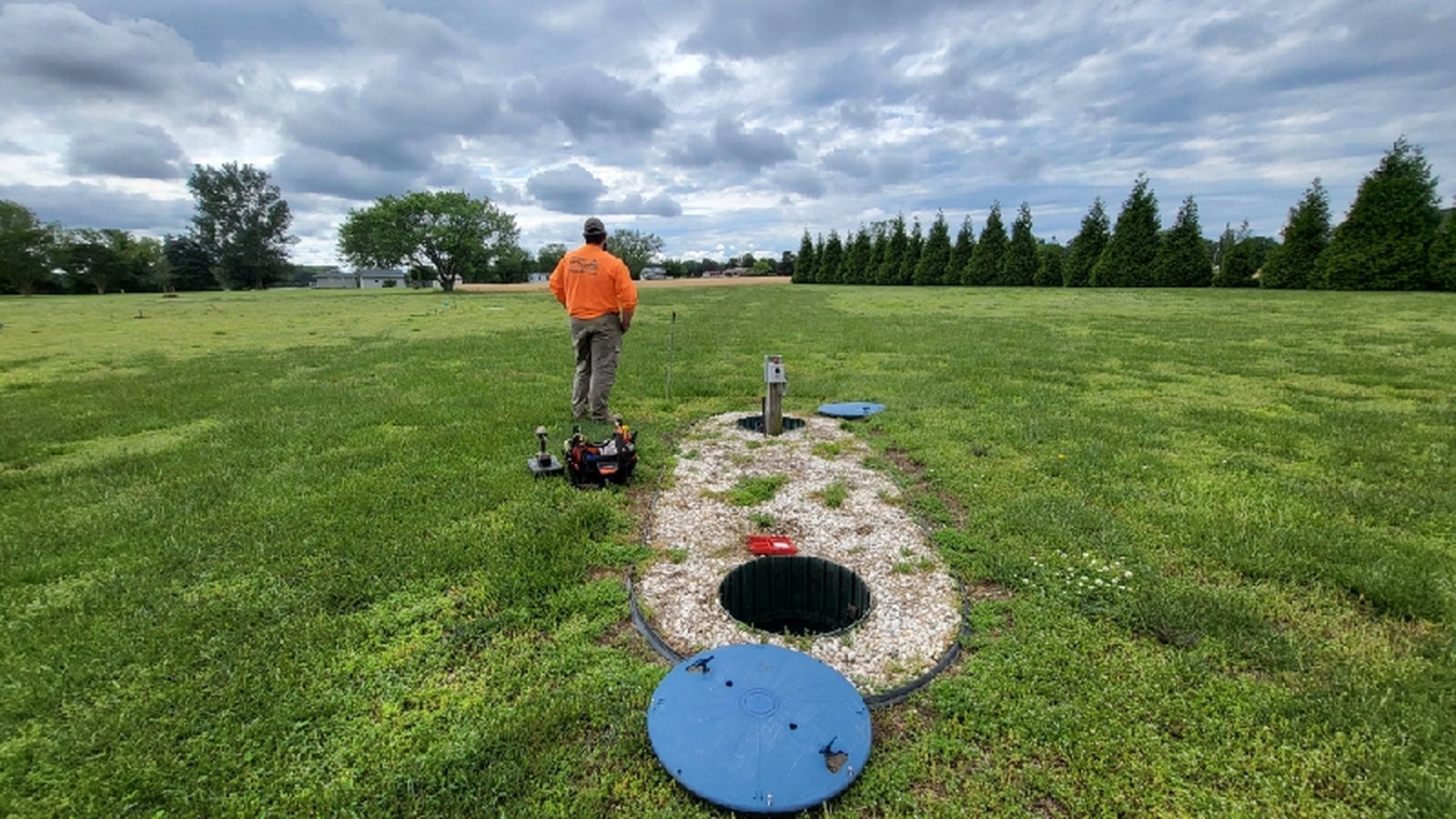 Man working in field near access hatch and grass areas