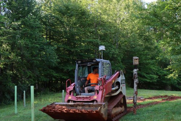 Bulldozer working on red soil in a green field