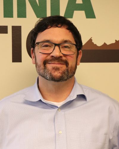 David man with beard and glasses smiling in front of wall