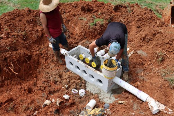 Pipeline repair in grassy area with workers and tools